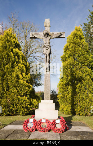 Pirbright Surrey England UK Stein Kruzifix Kriegerdenkmal mit roten Mohn Kränze in St. Michael Friedhof Stockfoto