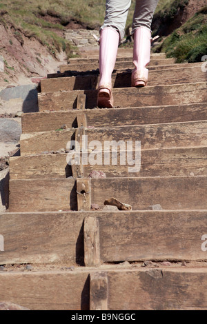 Junge Frau zu Fuß hinauf getragen Holzstufen, niedrigen Bereich, Rückansicht, West Dale, Pembrokeshire Stockfoto