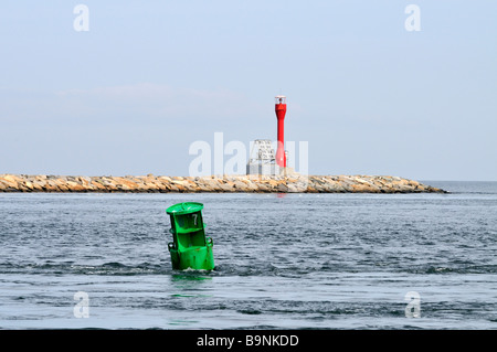 Navigations-Kanal Marker im Ozean mit einem grünen können und eine rote solar powered Daymarker auf steinernen Steg. Stockfoto