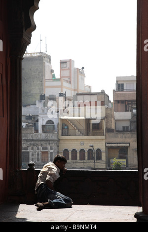 Ein Mann beugt sich über eine Kante einer Moschee mit Blick auf Delhi, Indien. Stockfoto