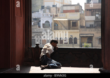 Ein Mann beugt sich über eine Kante einer Moschee mit Blick auf Delhi, Indien. Stockfoto