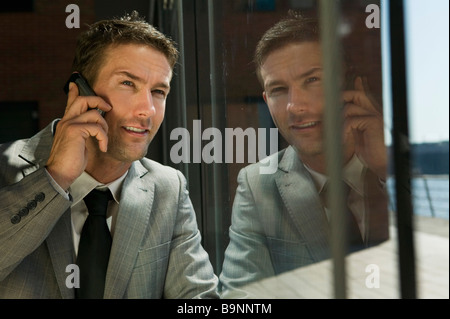 Porträt der Geschäftsmann gegenüber Fenster telefonieren mit Handy Stockfoto