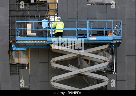 Arbeiter mit einem Scherenhubtisch Verkleidung in ein neues Gebäude an der Lancaster University passen Stockfoto