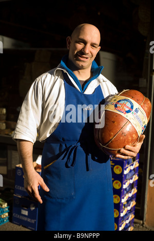 Ein Metzger hält einen großen Schinken in der Tür seines Ladens in der Mercato di Mezzo Bologna Italien Stockfoto