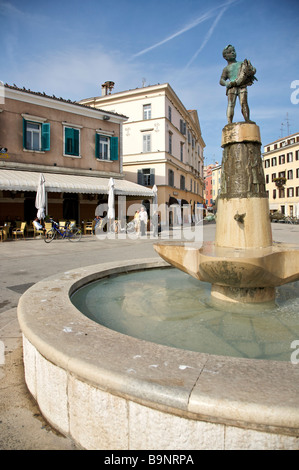 Brunnen mit Bronze-Statue im wichtigsten Platz Trg Marsala Tita, Rovinj, Istrien, Kroatien mit Cafés & Gebäude im Hintergrund Stockfoto