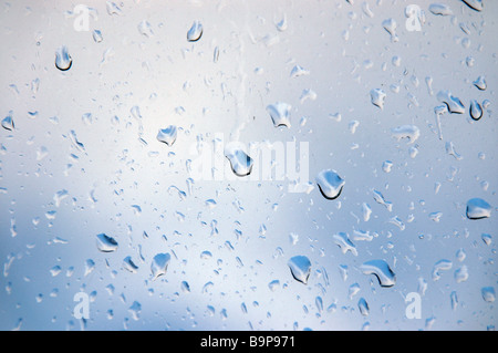 Regentropfen auf einem Fenster mit Blick auf einen aufhellenden Himmel. Stockfoto