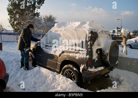 Mann, Schaben Schnee vom Auto in der Einfahrt. Stockfoto