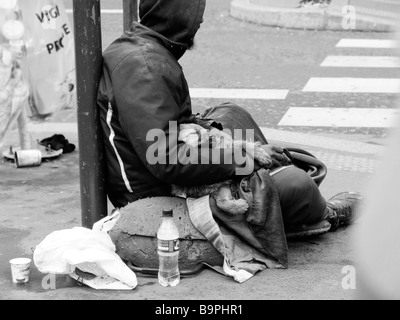 Obdachloser sitzt auf den Straßen von Paris mit einem jungen Welpen, der auf seinem Schoß schläft. Paris Frankreich Europa Stockfoto