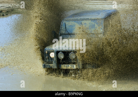 Ein Land Rover Defender 90 beschleunigt durch eine überschwemmte Straße in Slindon West Sussex UK während einer Off Road-Übung Stockfoto