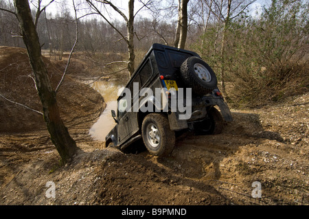 2007-Entwurf Land Rover Defender 90 kriecht eine steile Böschung hinunter zu einem Teich in Slindon West Sussex UK während einer Off Road-Übung. Stockfoto