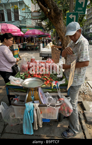 Eine thailändische Frau kauft frische Erdbeeren von einem Straßenstand in Bangkok Thailand Stockfoto