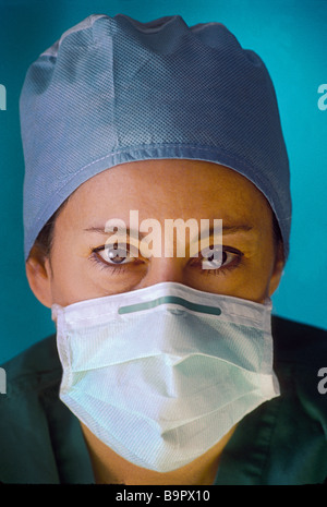 Weibliche Chirurg mit betroffenen Ausdruck, tragen von Mundschutz und scheuert. Stockfoto
