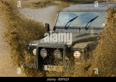 Ein Land Rover Defender 90 plätschert durch einen Fluss. Stockfoto