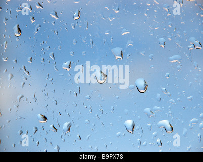 Regentropfen auf einer Fensterscheibe, Blick auf einen aufhellenden Himmel. Stockfoto