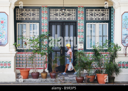 Frau zu Fuß vorbei an traditionellen Häusern im Kolonialstil In Singapur Stockfoto