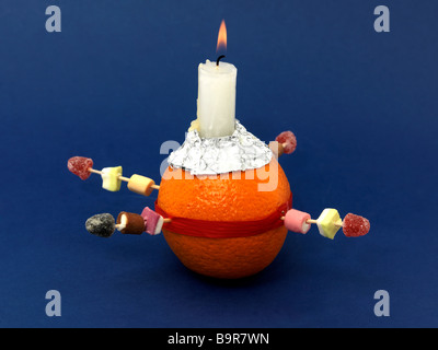 Christingle Orange symbolisiert die Welt, Kerze Jesus Christus das Licht der Welt, rotes Band das Blut Christi und die vier Süßigkeiten die vier Ecken Stockfoto