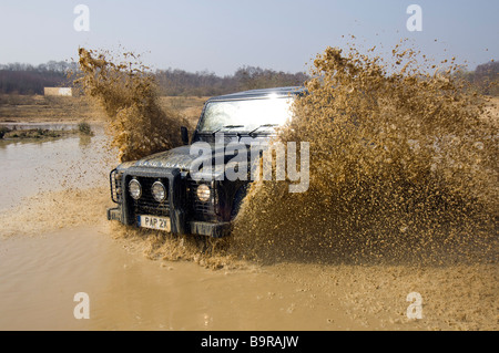 Ein Land Rover Defender 90 beschleunigt durch eine überschwemmte Straße in Slindon West Sussex UK während einer Off Road-Übung Stockfoto