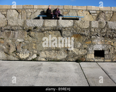 Zwei Frauen sitzen auf dem Pier in Dun Laoghaire Co Dublin Irland Stockfoto