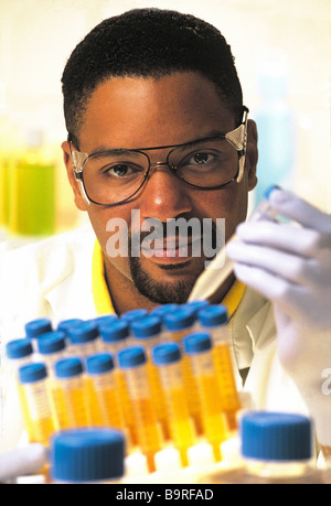 Männlichen Afroamerikaner Laborantin im Forschungslabor, hält Reagenzgläser, weißen Laborkittel und Schutzbrille tragen. Stockfoto