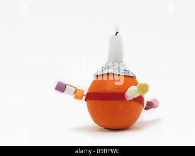 Christingle Orange symbolisiert die Welt, Kerze Jesus Christus das Licht der Welt, rotes Band das Blut Christi und die vier Süßigkeiten die vier Ecken Stockfoto