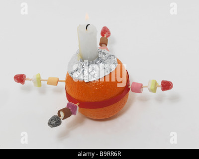 Christingle Orange symbolisiert die Welt, Kerze Jesus Christus das Licht der Welt, rotes Band das Blut Christi und die vier Süßigkeiten die vier Ecken Stockfoto