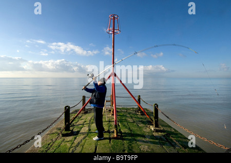 Angler Ken Jeffers wirft seine Rute Linie und Köder in einem ruhigen Meer aus einer Buhne mit ein Leuchtfeuer in Hove East Sussex UK Stockfoto