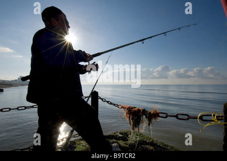 Ein Angler wirft seine Linie in einem ruhigen Meer aus einer Buhne Hove Beach kurz nach Sonnenaufgang. Stockfoto