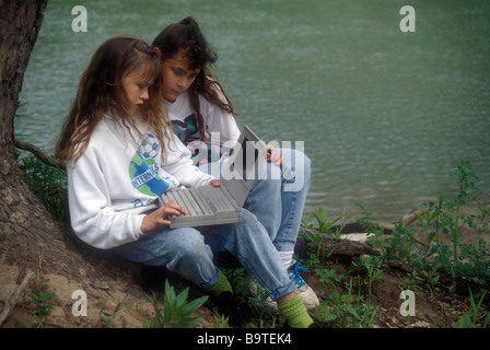 Junge Mädchen teilen Laptop vom Gewässerrand Stockfoto