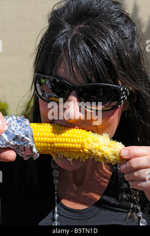 Weiße Kaukasische Frau mit Sonnenbrille isst Mais auf Cob bei Imbissstände am Lake Wales Karneval Feier Florida zentral-USA Stockfoto