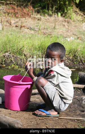 Ein Junge sammelt das Wasser aus einem schmutzigen Fluss, Madagaskar, Afrika Stockfoto