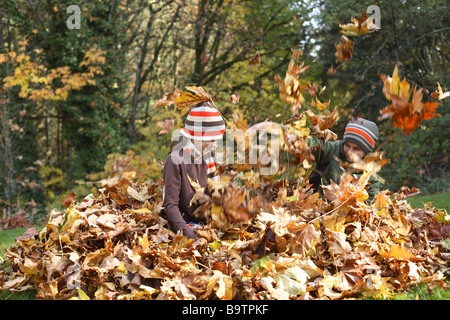 Kinder spielen im Herbstlaub Stockfoto