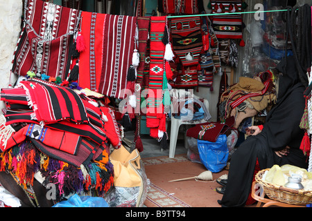 Qatari Frau Recht in ihren schwarzen Abaya Mantel gehüllt wird fast unsichtbar in ihr Textilgeschäft, Souq Waqif Doha Katar Stockfoto