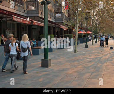 MENSCHEN, DIE IN DER ABENDDÄMMERUNG AUF DEM WEG ENTLANG DER SOUTHBANK, MELBOURNE, VICTORIA, AUSTRALIEN LAUFEN Stockfoto