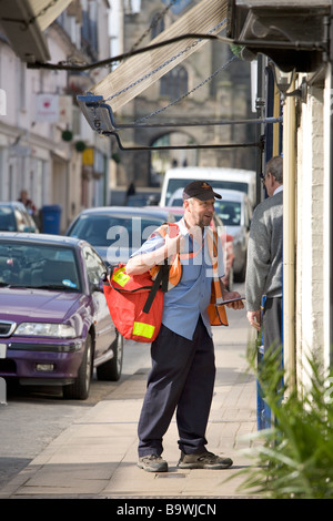 Royal Mail Postbote liefert Briefe und spricht ein Ladenbesitzer in der historischen Stadt Warwick, Warwickshire, UK. Stockfoto