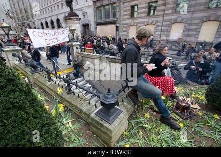 G20-Demonstration 2009: Londoner Demonstranten teilen sich eine Tasse Tee im Garten vor der Bank of England, mit der Flagge "Verbraucher lutschen" im Hintergrund Stockfoto