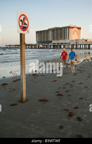 Zwei Männer Spaziergang mit seinem Hund am Strand von Galveston mit dem Flaggschiff-Hotel im Hintergrund. Stockfoto