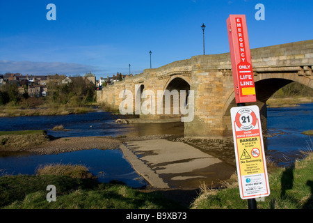 Landschaftsblick auf die historische alte Steinbrücke bei Corbridge Northumberland mit lebensrettende Sicherheit Linie Dispenser im Vordergrund Stockfoto