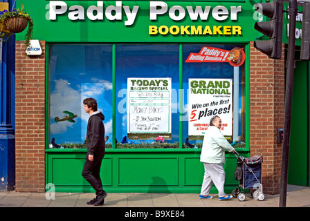 junger Mann und eine ältere Dame übergeben durch einen Zweig der Paddy Power Buchmacher Stockfoto