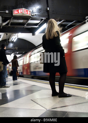 Ein Film wie Bild einer jungen Frau, die darauf warten, in einem Londoner U-Bahn Zug bekommen, da es in die Station stürmt. Stockfoto