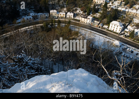 Blick auf Schnee in Matlock Bath Derbyshire England Blick durch Bäume in Richtung Künstler-Ecke und der A6 Straße unten Stockfoto