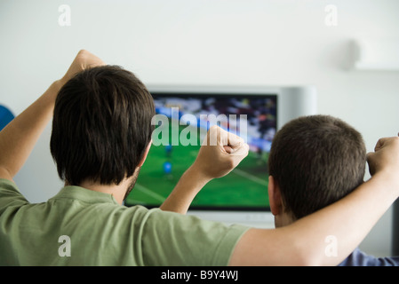 Zwei Männchen Sportübertragungen im Fernsehen, Fäuste, aufgewachsen in Luft, Rückansicht Stockfoto