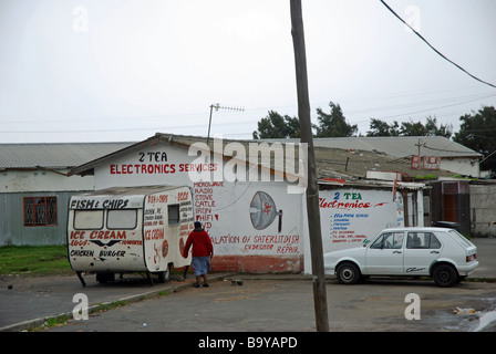 Ein Wohnwagen Verkauf Fisch und Chips und Räumlichkeiten, die Werbung, den Verkauf und die Reparatur von High-Tech-Produkten, Township Langa, Kapstadt Stockfoto