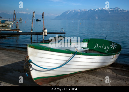 Ein Boot am Genfer See, umrahmt von den Alpen an der Marina in Ouchy, Lausanne, Schweiz Stockfoto