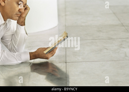 Senior woman liegen auf gefliesten Boden Buch Stockfoto