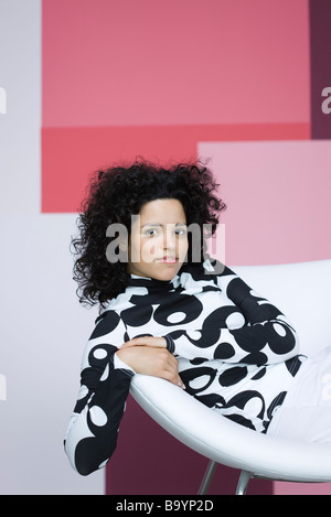 Junge Frau sitzt im Stuhl, lächelnd in die Kamera, Porträt Stockfoto