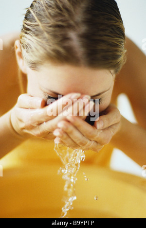 Frau Gesicht im Waschbecken waschen Stockfoto