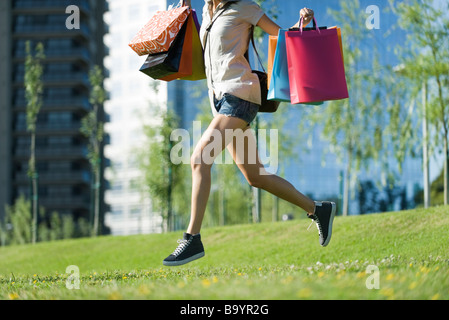 Junge Frau im Park, Einkaufstaschen tragen Stockfoto