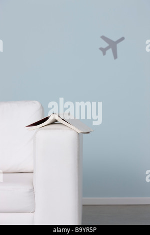 Buchen Sie am Arm des Sofas, Flugzeug im Hintergrund Stockfoto