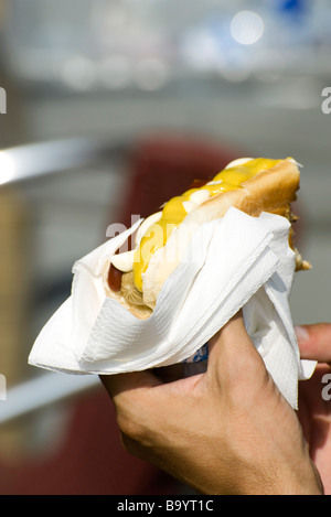 Hand mit Hotdog im Brötchen mit Ketchup und Senf Stockfoto