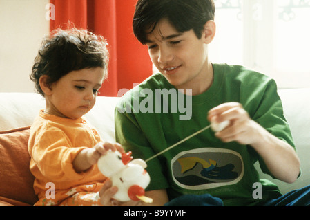 Jungen spielen mit Schwesterchen und Spielzeug Ente Stockfoto